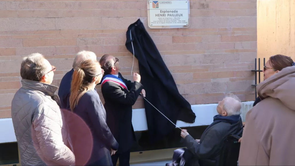 Un groupe de personnes se trouve devant la pancarte Henri Pailleux : Henri Pailleux lui-même, au premier plan, assis sur un fauteuil roulant, le maire portant une écharpe tricolore, ainsi qu'Aurore Bergé, députée des Yvelines.